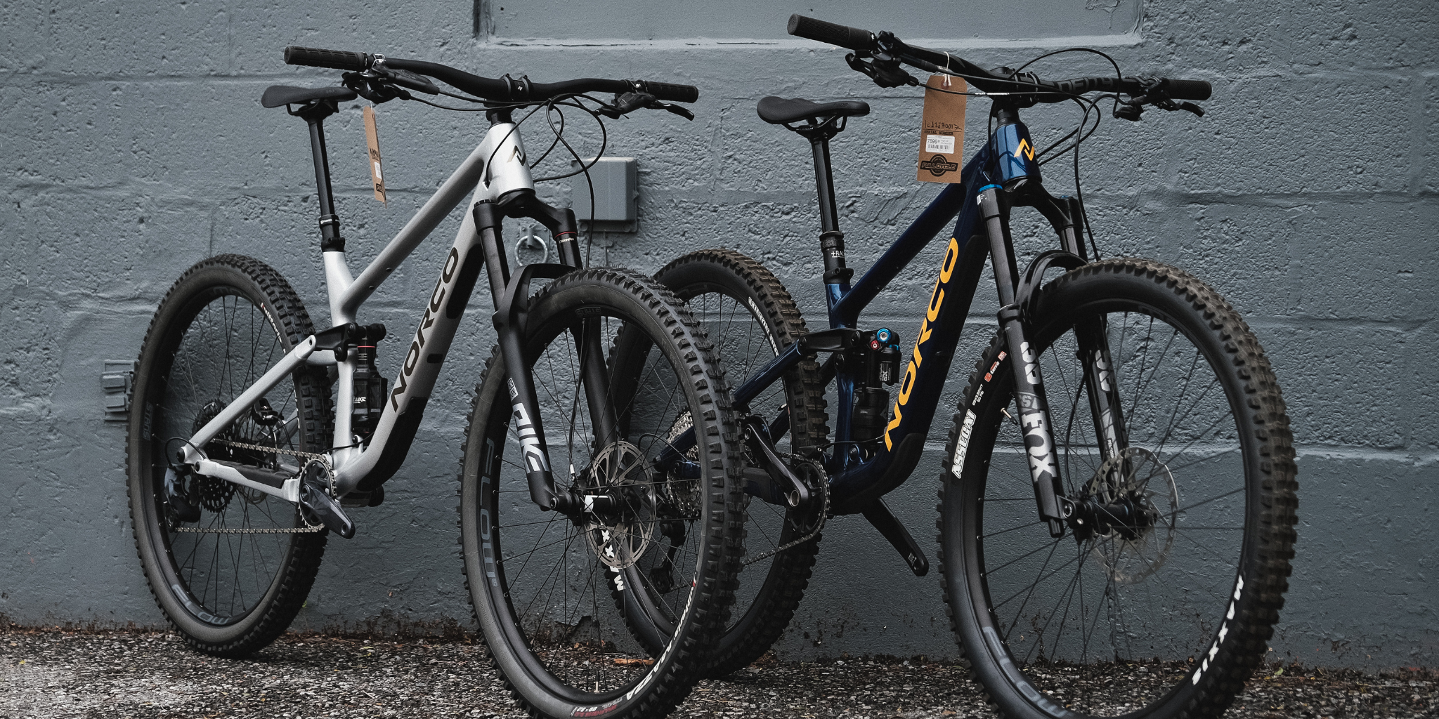 two Norco bikes in front of a grey wall 