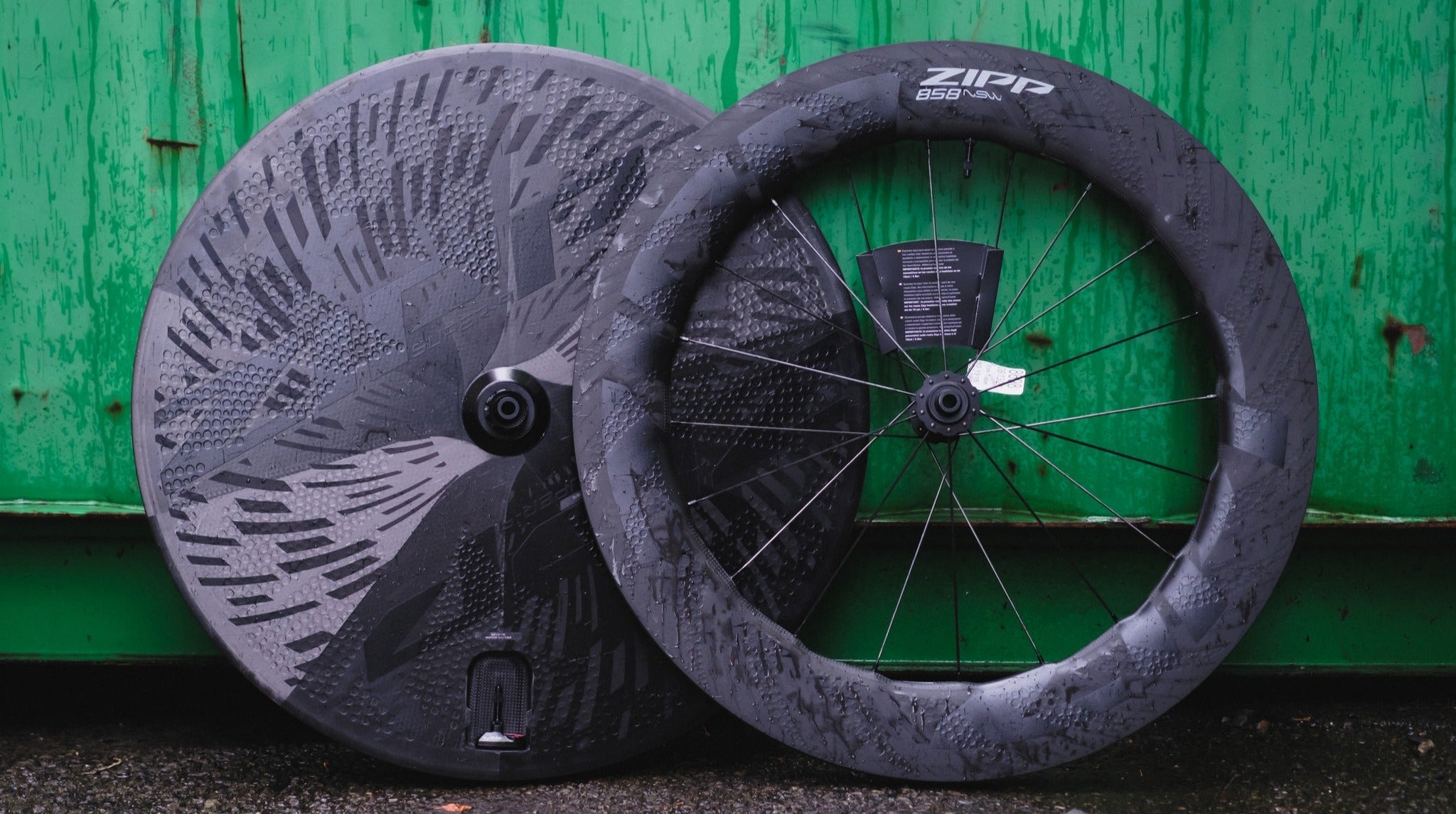 Two bicycle wheels with Zipp branding against a green wooden background