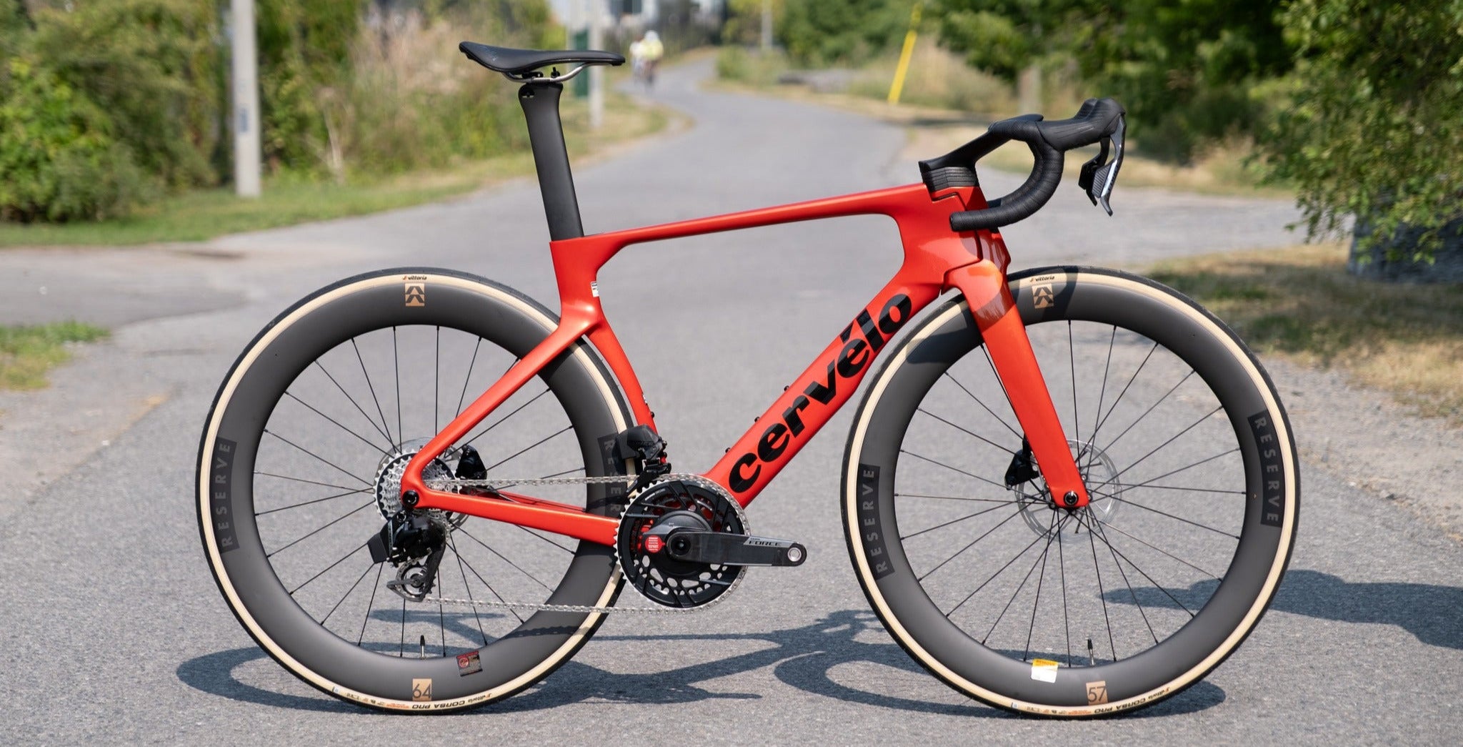 Red bicycle with 'Cervelo' branding on a road with greenery in the background