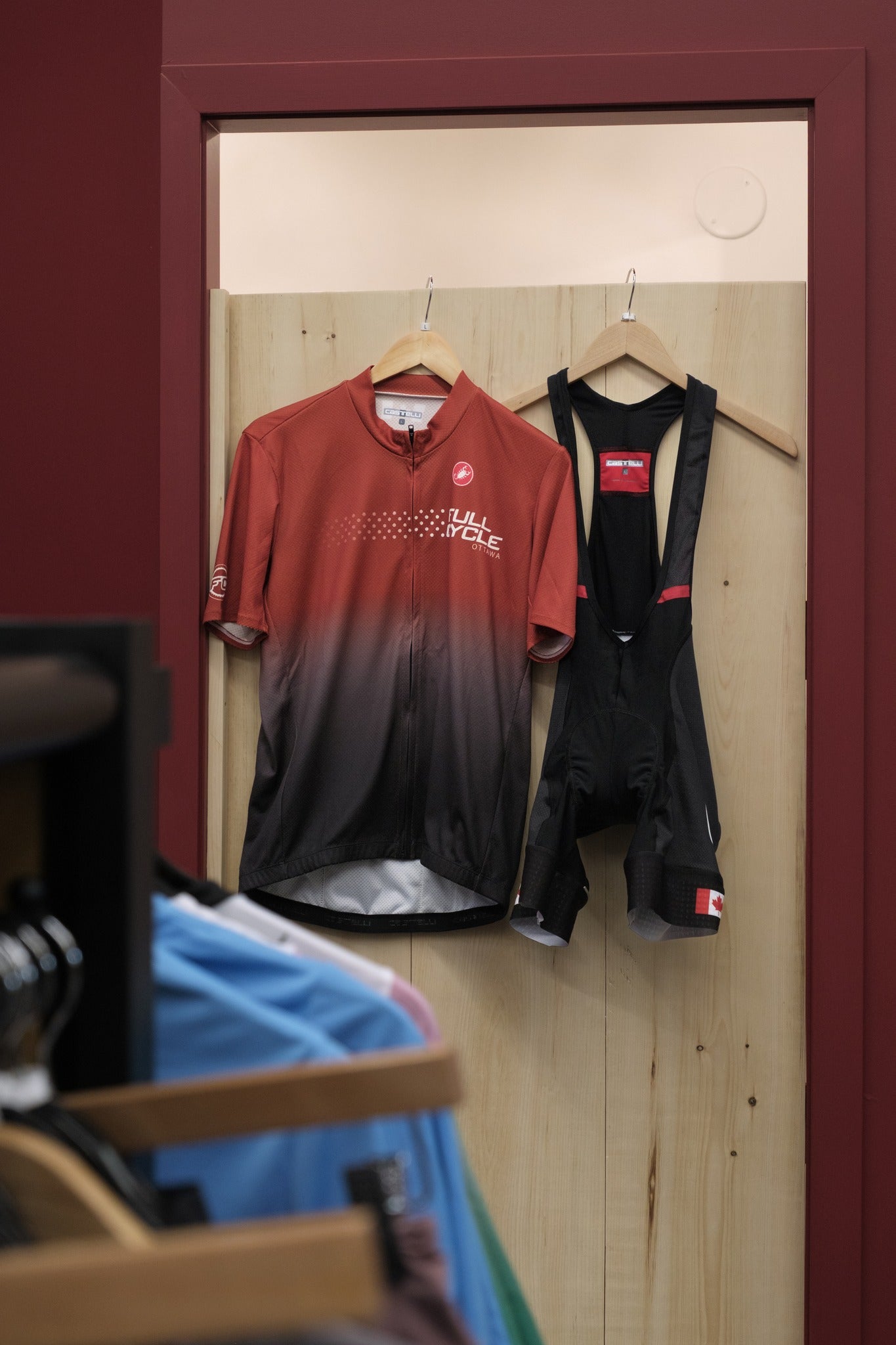 Red and black cycling outfit hanging on a wooden door