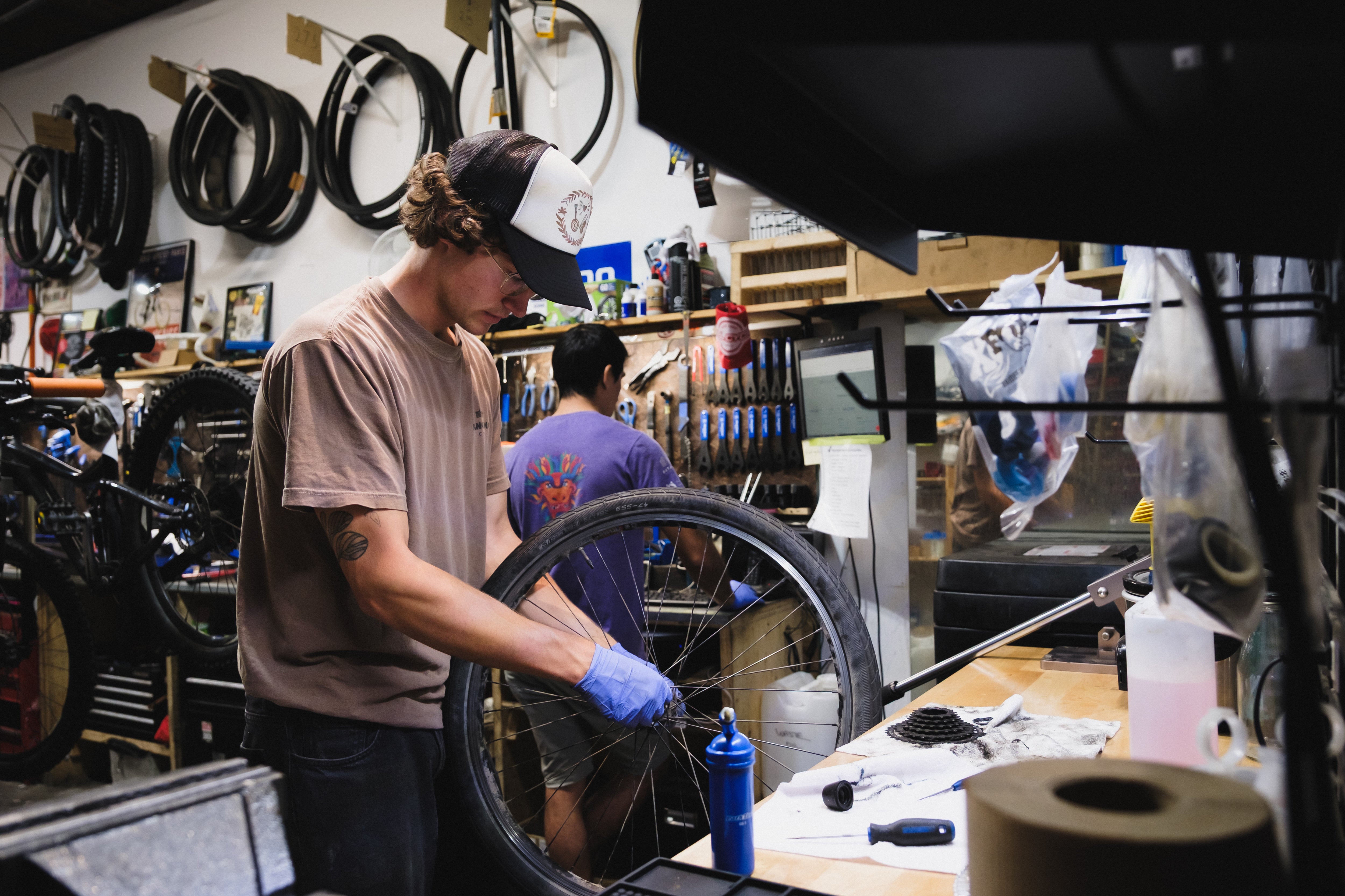 Person working on a bicycle wheel in a workshop setting