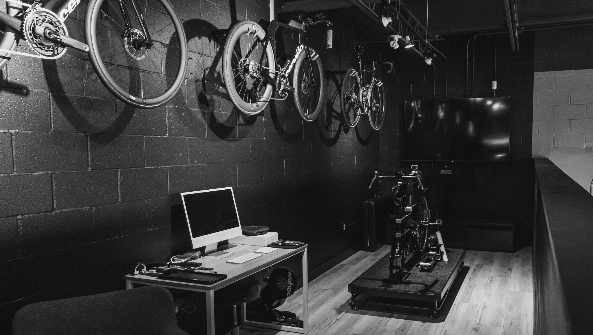 Bicycles mounted on a wall in a room with a desk and computer.